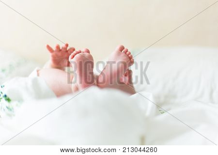 Baby feets, heels, hands in white bed