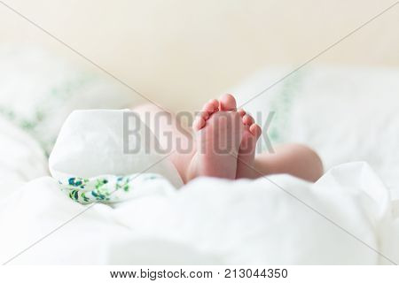 Baby feets, heels, hands in white bed