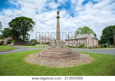 CUMBRIA, ENGLAND - JUNE 14, 2016 - Stone cross in the village of Greystoke, Cumbria. The village is on the route of the Coast to Coast cycleway from Whitehaven to Tynemouth in Northern England.