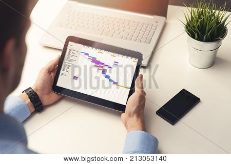 project manager looking at gantt chart on digital tablet in office