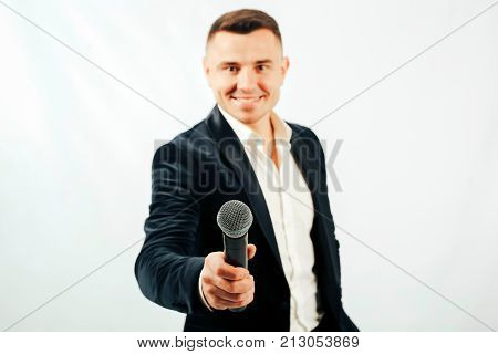 smiling young man in a suit with a microphone in hands on a white background.