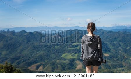 The girl carry black camera and see the beautiful world on the top of Mountain at Phu Koon : Vang Vieng Laos
