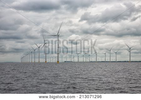 Large offshore windfarm near Dutch coast with cloudy sky. This park in the lake IJssselmeer near Urk is the biggest windfarm of the Netherlands