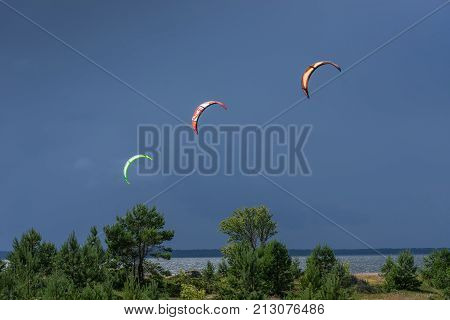 A kite surfer rides on the sea. Kites in the sky. Kite Boarding extreme sport on Mohni small island in Estonia Europe.