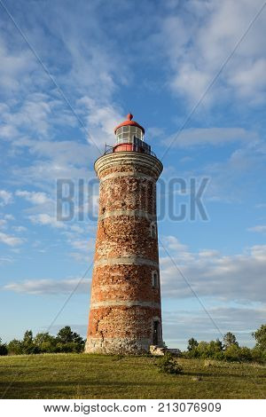 Lighthouse and house in the Baltic Sea. Shore evening light sunset clouds and architecture concept. Mohni small island in Estonia Europe.