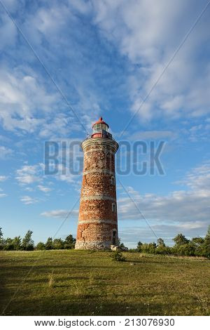 Lighthouse and house in the Baltic Sea. Shore evening light sunset clouds and architecture concept. Mohni small island in Estonia Europe.