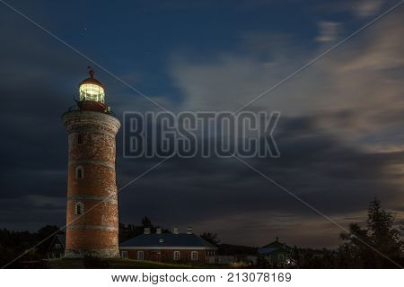 Lighthouse and house in the Baltic Sea. Shore evening light sunset clouds and architecture concept. Mohni small island in Estonia Europe.