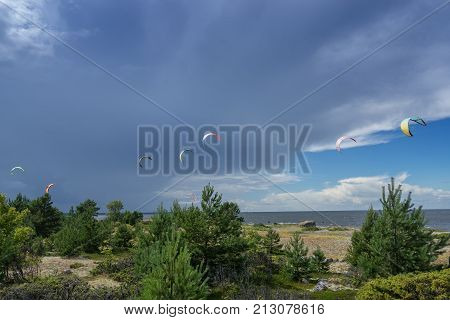 A kite surfer rides on the sea. Kites in the sky. Kite Boarding extreme sport on Mohni small island in Estonia Europe.