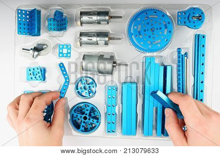 Unpacking DIY kit above view. Hands take metal part of rc model