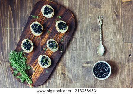 Top view of black caviar appetizers at wooden board
