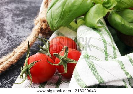 Cherry tomatoes with basil and dish towl on cutting board.