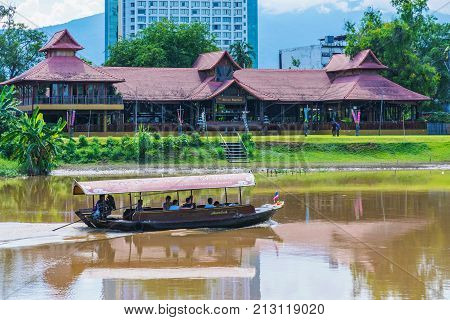 CHIANG MAI THAILAND - JULY 29: This is a view of a tourboat and riverside buildings along the famous Ping river on July 29 2017 in Chiang Mai