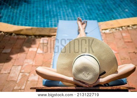 Women wearing bikini or swimware suits at swimming pool relax on the pool bed at the resort of Pattaya in Thailand.