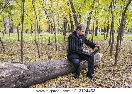 Businessman Having A Laptop In The Park In The Fall. A Man Is Working At A Computer In The Park.