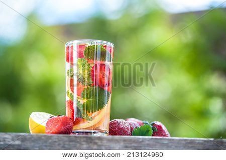 A glass of detox water. Strawberry lemon and mint with cool clean water backdrop of a green garden. Detox diet Cookery sports proper nutrition sports nutrition body cleansing