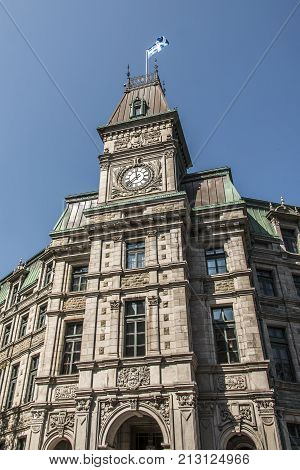 Classic clocktower building in Quebec City Canada with flag of quebec on a sunny day blue sky
