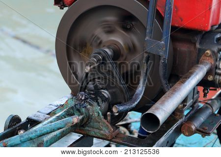 Men are repairing engines adapted for long-tail boats. Maintenance the chain gear and equipment for modified old diesel engine and spare parts in Thailand.