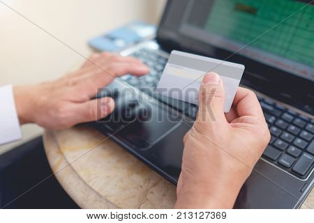 Young Asian Businessman sitting with laptop and holding Credit Card pay for online Shopping Online Shopping for Men concept