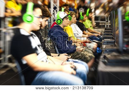 ROME, ITALY. October 03, 2015: Boys tournament players and gaming consoles. Row of young boys playing with a console. Wearing headphones. Romics 2015 in Rome, Italy. Festival of comics and gaming.