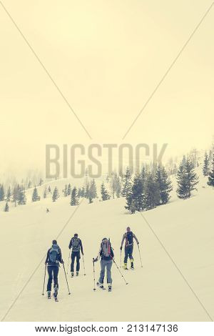Group of back country skiers walking through a misty valley. Exploring winter fairytale.