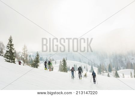 Group of back country skiers walking through a misty valley. Exploring winter fairytale.