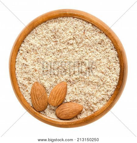 Shelled and ground almond nuts in wooden bowl. Edible, dried, brown seeds of Prunus dulcis. Ingredient in marzipan, nougat, cookies. Isolated macro food photo close up from above on white background.