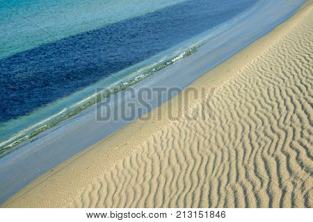 Sands on the beach.
A beach is a landform along a body of water. It usually consists of loose particles, which are often composed of rock, such as sand, gravel, shingle, pebbles.