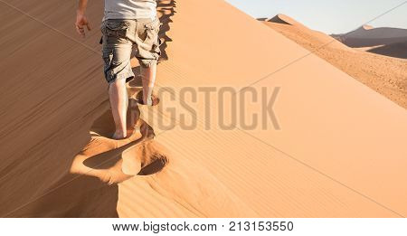 Lonely man walking on sand crest at Dune 45 in Sossusvlei desert - Wanderlust concept with hiker guy in namibian famous place - Adventure trip travel to african wonder in Namibia - Bright natural tone
