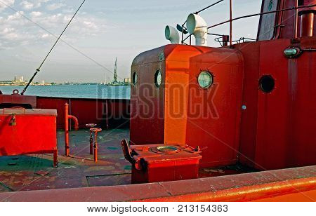 An old red lightship which has served the seas for over a century rests in its harbour in the afternoon sun. It sharply shows hinges, nuts , bolts, steel plates, welded repairs, rust and the infuence of time. The background is 'romantically' blurred but s