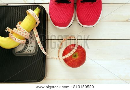 Black weight scale ,fresh fruit and measure tap on white wooden floor Fitness concept,diet and exercise  for losing weigh