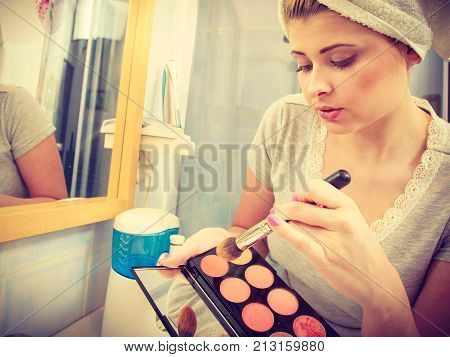 Woman In Bathroom Applying Contour Bronzer On Brush