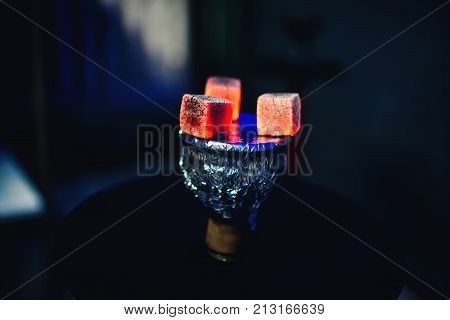 bowl of hookah tobacco for Smoking with hot coals on the foil on a dark background for a traditional Asian holiday