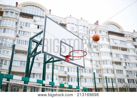 Basketball ring on the background of high-rise buildings. Flying in the air basketball in the ring.