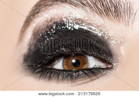 Smoky eyes. Beautiful macro female eye with long eyelashes and smoky makeup. Eyebrows and long lashes. Cosmetics make-up. Closeup fashion eyes visage makeup close-up. Eyebrow makeup