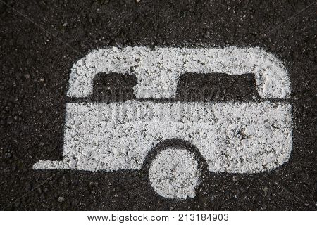 white caravan is painted on the asphalt on a parking spot for caravans