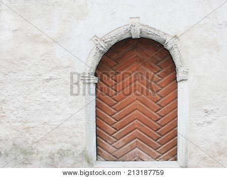 Ancient Archway with Wooden Door against Old Vintage Building Wall Background. Medieval Style Simple Architecture with Empty Copyspace. Bright Picture of House Facade during Summer Season Scene.