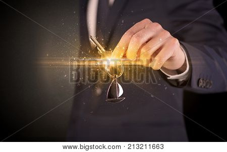 Businessman hand  over shiny keys in dark suit with dark background