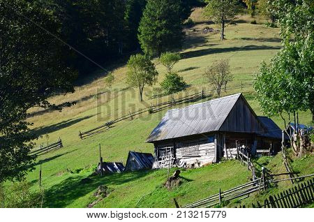 The Old Ukrainian Hut With A Slate Roof And A Wooden Fence In A Green Field