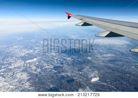 View of airplane wing abowe the clouds and land