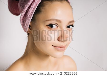 attractive girl with clean skin, with a pink towel on her head looking at the camera and smiling