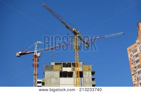 two cranes against the blue sky. construction of a multi-storey building