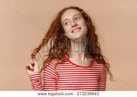 Indoor Closeup Of Young Redhead European Female Pictured Isolated On Peach Background Dressed In Str