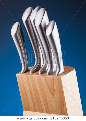 steel knifes in wooden block on the blue background
