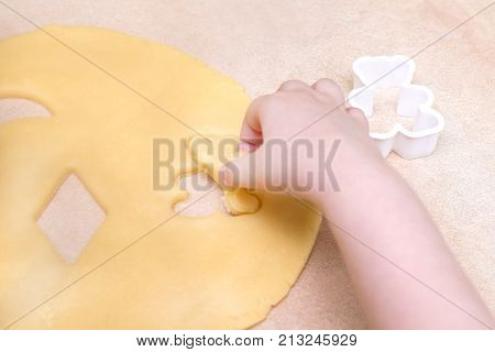 Children's hands make christmas cookies. Children's hands holding cookies of raw dough for christmas
