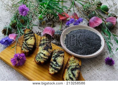 Sweet bun with flax seed and poppy and cup of tea on table.