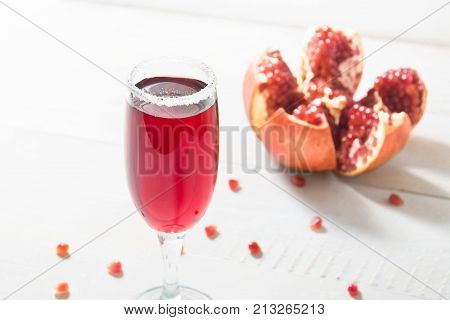 Pomegranate Beverage In Wineglass Over Wnite Wooden Table