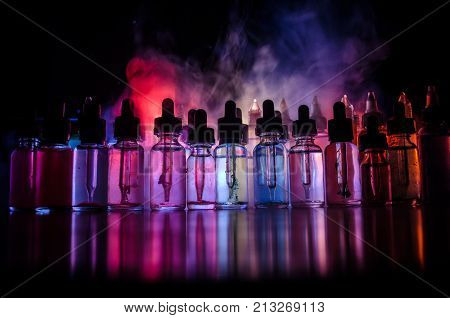Vape Concept. Smoke Clouds And Vape Liquid Bottles On Dark Background. Light Effects. Useful As Back