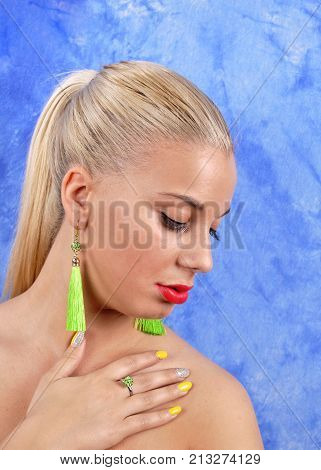 young beautiful girl in gren earrings on an abstract background.