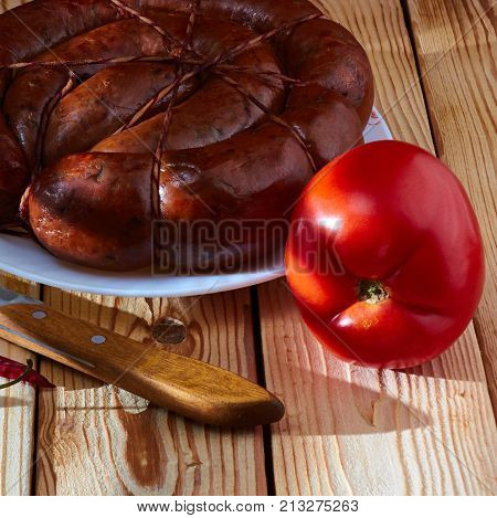 Preparation of a festive table on a table of smoked sausage a tomato onions and acute red pepper to improve apetit.