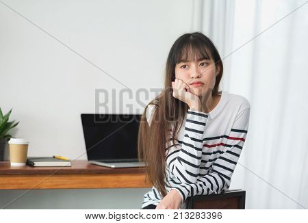 asia woman bored about working at cafe restaurantFemale rest chin on hand with stress feeling with laptop and coffee cup on table in coffee shopBoring work concept.